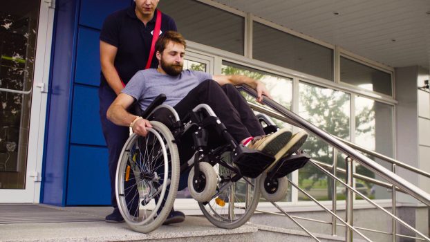 Man helping to move down to a disabled man